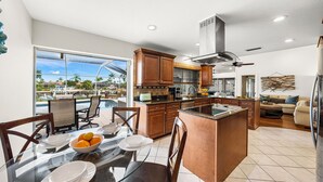 Une cuisine spacieuse dotée d’un grand îlot central, de meubles en bois et offrant une vue sur une piscine.