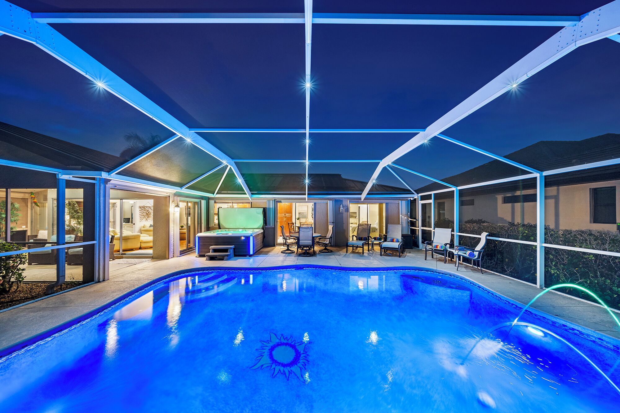 Een buitenzwembad met een overdekte patio, zitplaatsen en een jacuzzi.