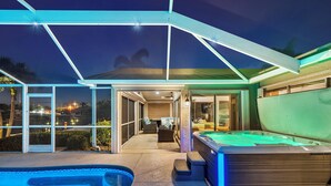 Un espace extérieur abrité comprenant un jacuzzi, une piscine et une terrasse avec des sièges.