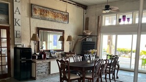 A spacious dining area with a large table and chairs, a ceiling fan, and a view of the outdoors. - The Purple Martin Inn (Rogers City)