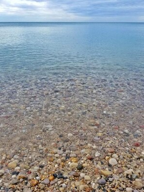 Una playa de guijarros con agua cristalina y un mar tranquilo.
