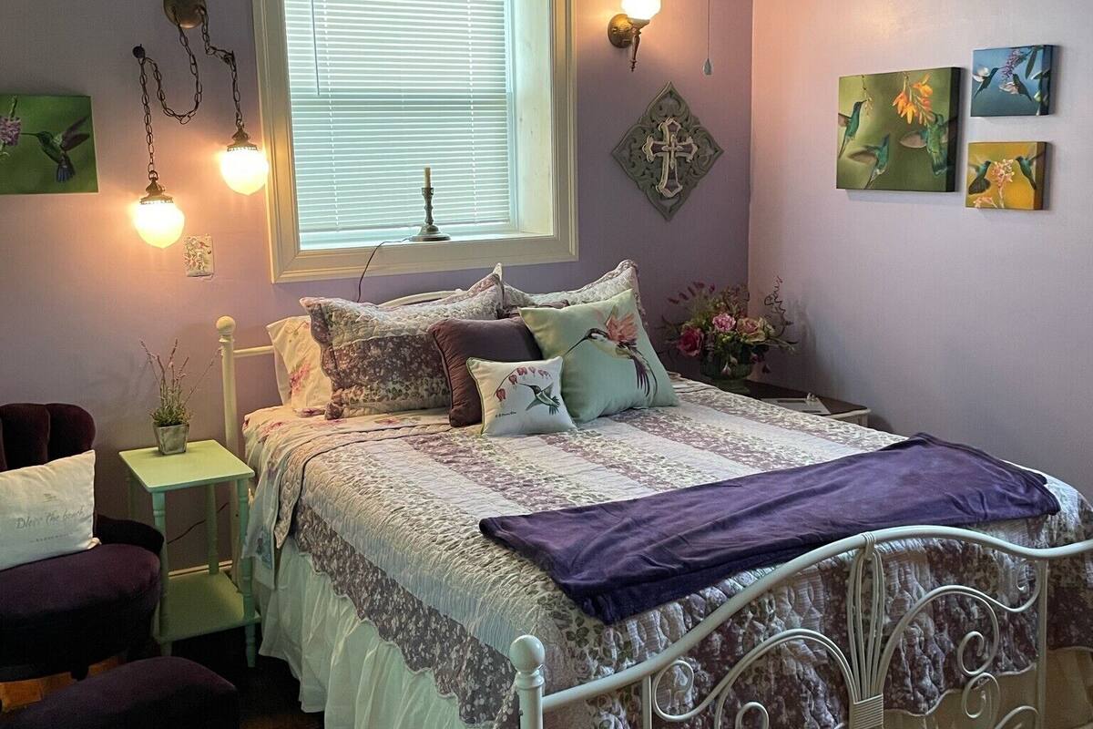 A bedroom with a bed, bedside tables, a window, wall art, and a ceiling fan.