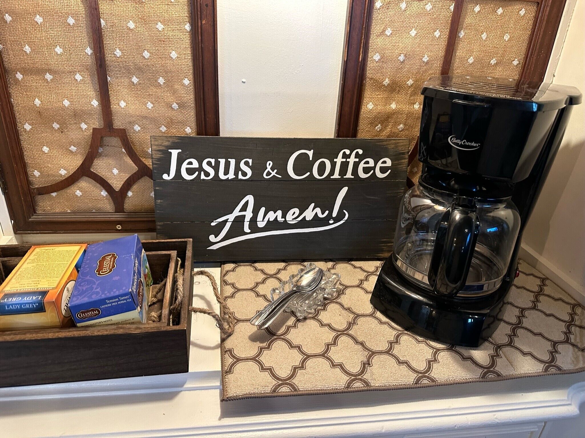 Een koffiezetapparaat, een bordje met de tekst 'Jesus & Coffee Amen!' en een doos Lady Grey thee op een aanrecht.
