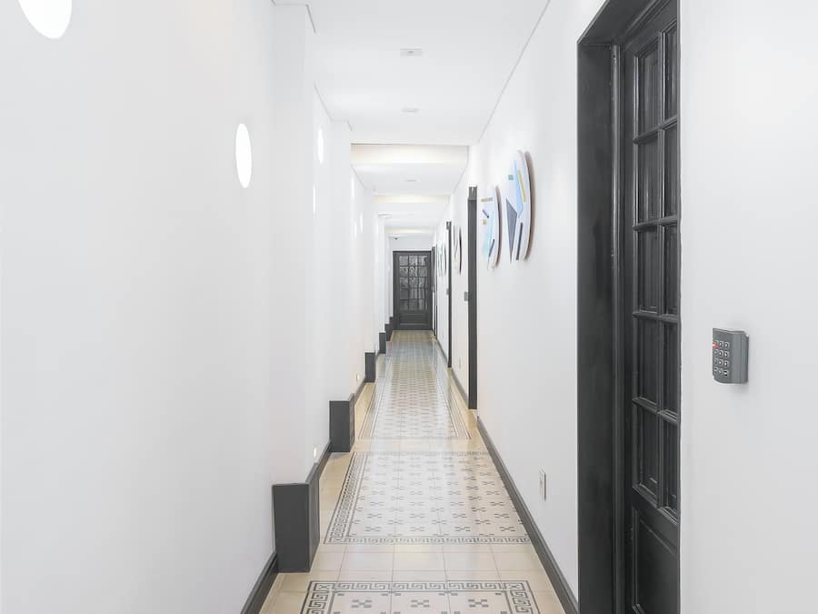 Un pasillo con piso estampado, iluminación empotrada y una puerta a la derecha.