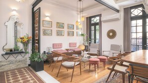 A spacious living room with a wooden dining table, cushioned seating, and a large window with curtains. - FAUNA Montevideo (Montevideo)