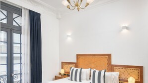 A hotel room with a large bed, wooden headboard, bedside lamps, and a chandelier. - FAUNA Montevideo (Montevideo)