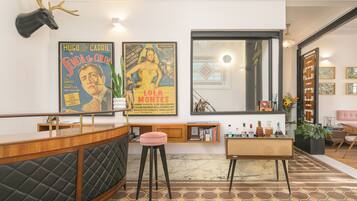 Una sala de estar moderna con una zona de bar, un espejo grande y dos carteles de películas antiguos.