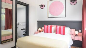Un dormitorio moderno con una cama grande, mesitas de noche con lámparas, un ventilador de techo y un espejo amplio.