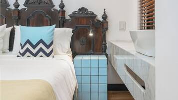 Un dormitorio con una cama grande, una mesita de noche, un aparador y un cabecero de madera.