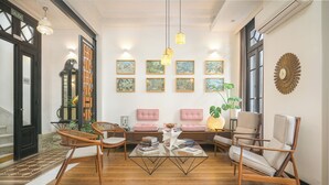 A spacious living room with a glass coffee table, wooden chairs, and a sofa. There are framed artworks on the wall and a large mirror. - FAUNA Montevideo (Montevideo)