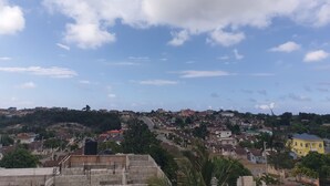 A residential area with houses, a road, and a hill in the background.