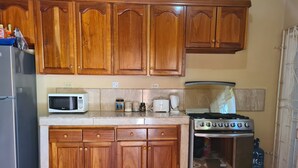 A kitchen with wooden cabinets, a microwave, a toaster, a coffee maker, a gas stove, and a refrigerator.