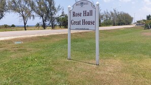 A sign for Rose Hall Great House with a clear view of the surrounding landscape.