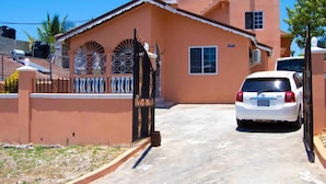 A residential house with a gated entrance, a parked white car, and a clear sky.