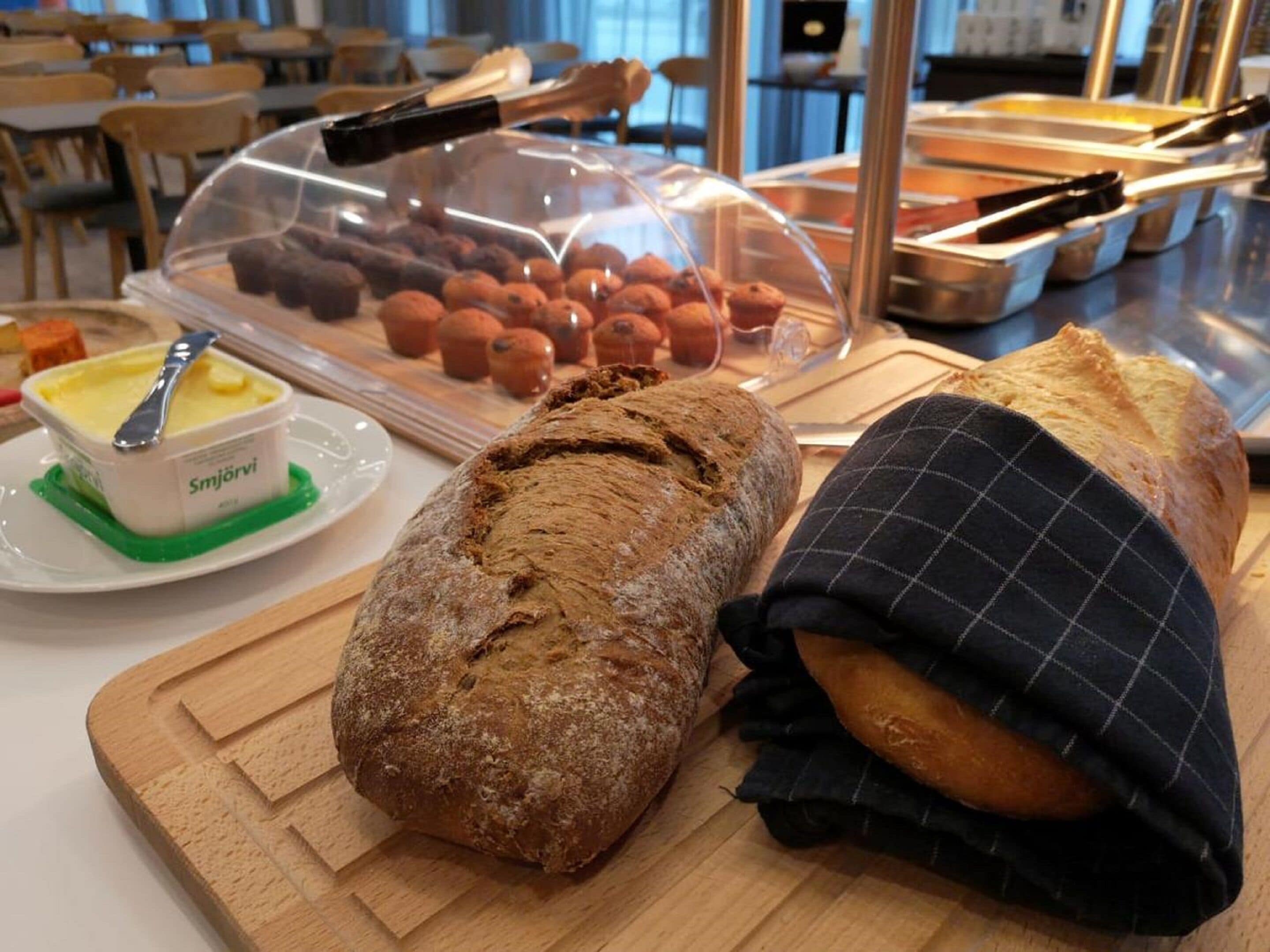 A buffet with various food items including bread, pastries, and a container of butter.