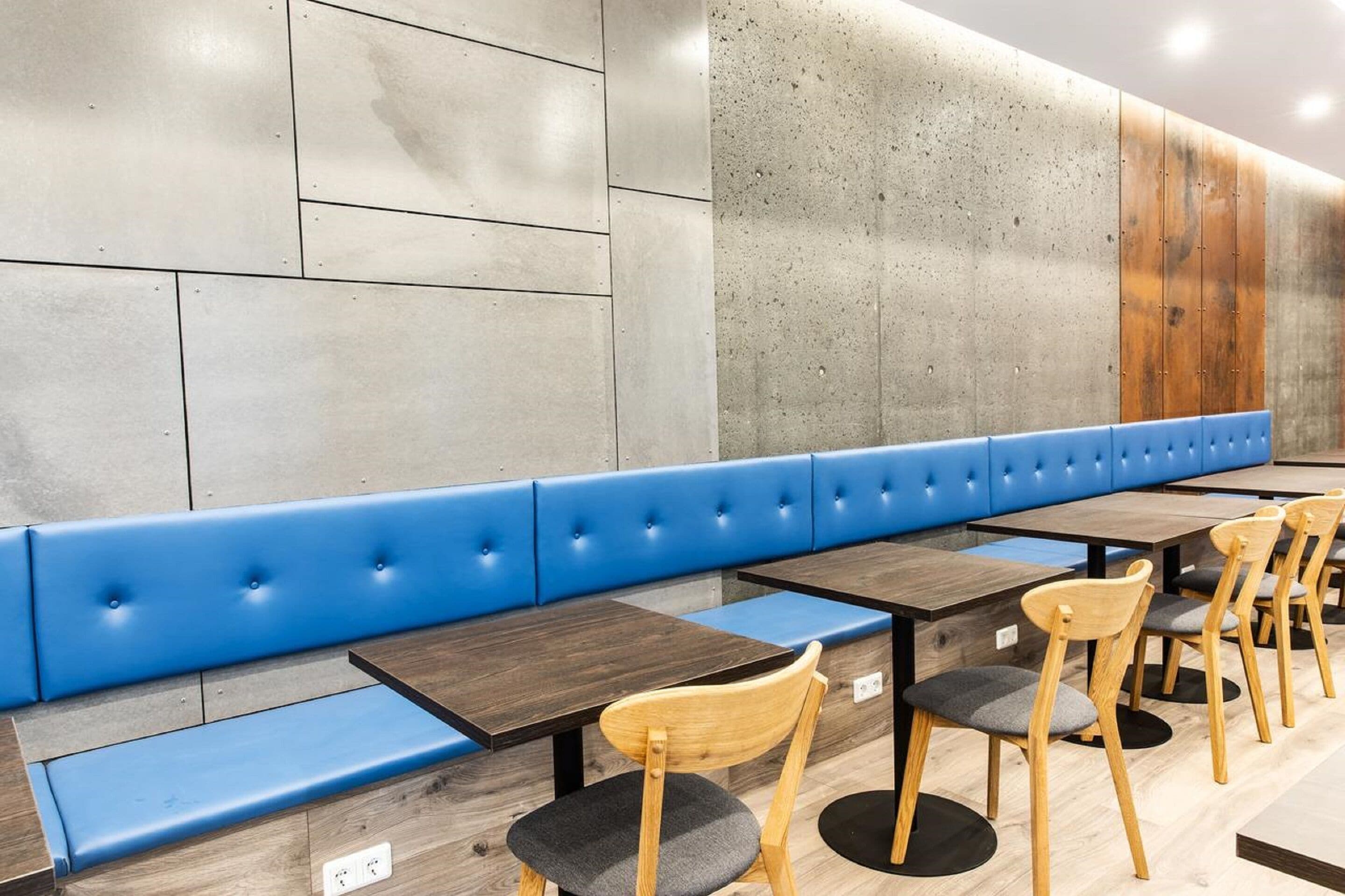 A restaurant interior with blue cushioned booths, wooden tables, and chairs.