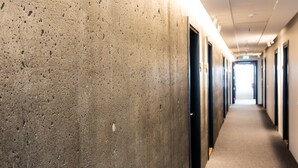A hallway with concrete walls and doors leading to rooms. - Hotel South Coast (Selfoss)