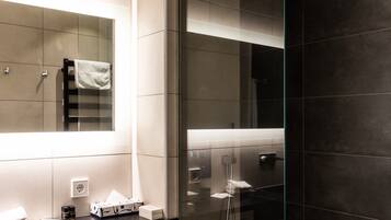 A modern bathroom with a glass shower enclosure, a white toilet, and a vanity with a mirror.