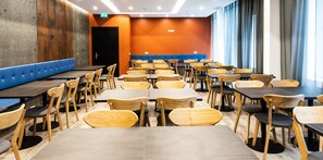 Un restaurante con varias mesas y sillas, un banco acolchado azul y una puerta con un letrero de salida.