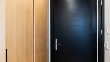 Un pasillo con piso de madera, una puerta negra y una lámpara colgante arriba.