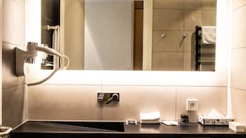 A modern bathroom with a large mirror, a towel rack, a sink, and a toilet.