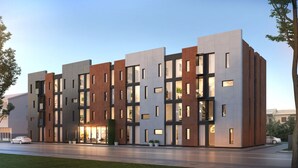 A modern multi-story building with a mix of glass and brick facades, large windows, and a well-maintained lawn in front. - Hotel South Coast (Selfoss)