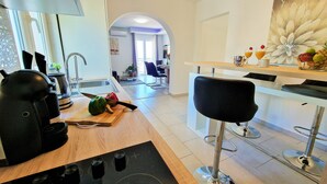 A modern kitchen with a wooden countertop, a coffee machine, and a cutting board with vegetables. - Holiday House Above with pool (Klis)