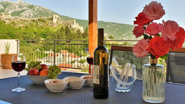A table set with wine, fruit, and flowers on a balcony with a mountain view. - Holiday House Above with pool (Klis)
