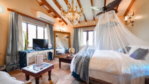 Un dormitorio con cama, televisor, escritorio y candelabro.