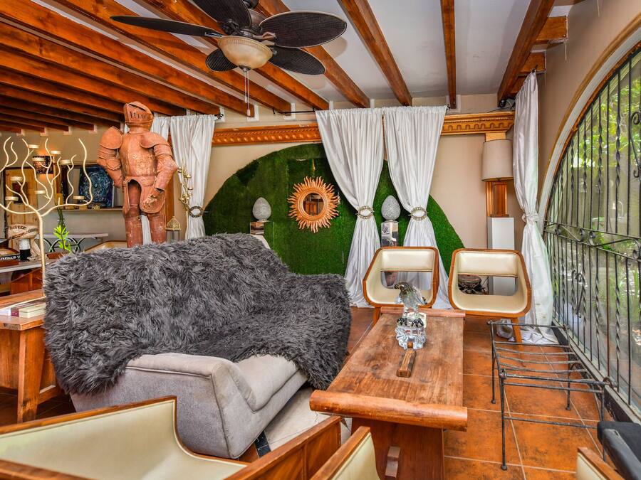 A cozy room with a wooden ceiling, a rustic sofa, a wooden table, and a metal gate.
