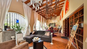 Amplia sala de estar con sofá, mesa de centro y obras de arte sobre caballetes.