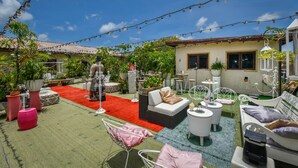 Un patio con mobiliario exterior, luces colgantes y plantas en macetas.