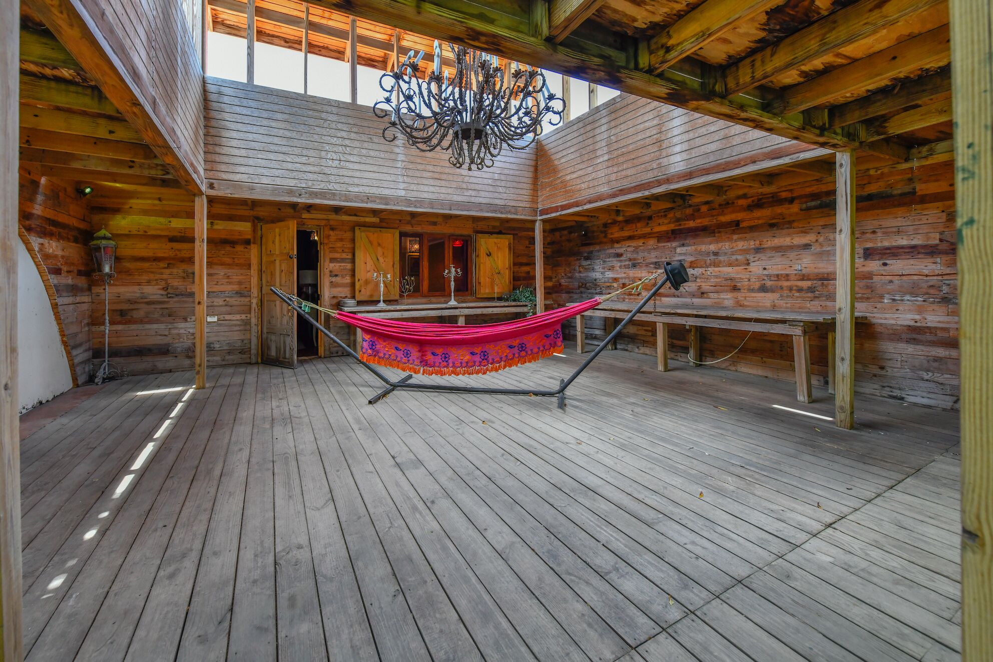 A spacious wooden cabin with a hammock, wooden floors, and a chandelier.