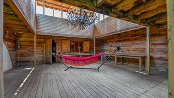 A spacious wooden cabin with a hammock, wooden floors, and a chandelier.