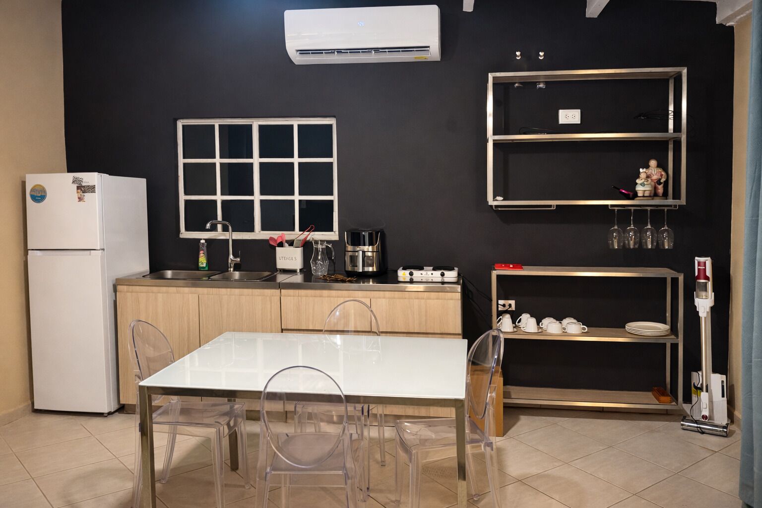 Une cuisine de taille réduite, avec un réfrigérateur blanc, une machine à café et un évier.