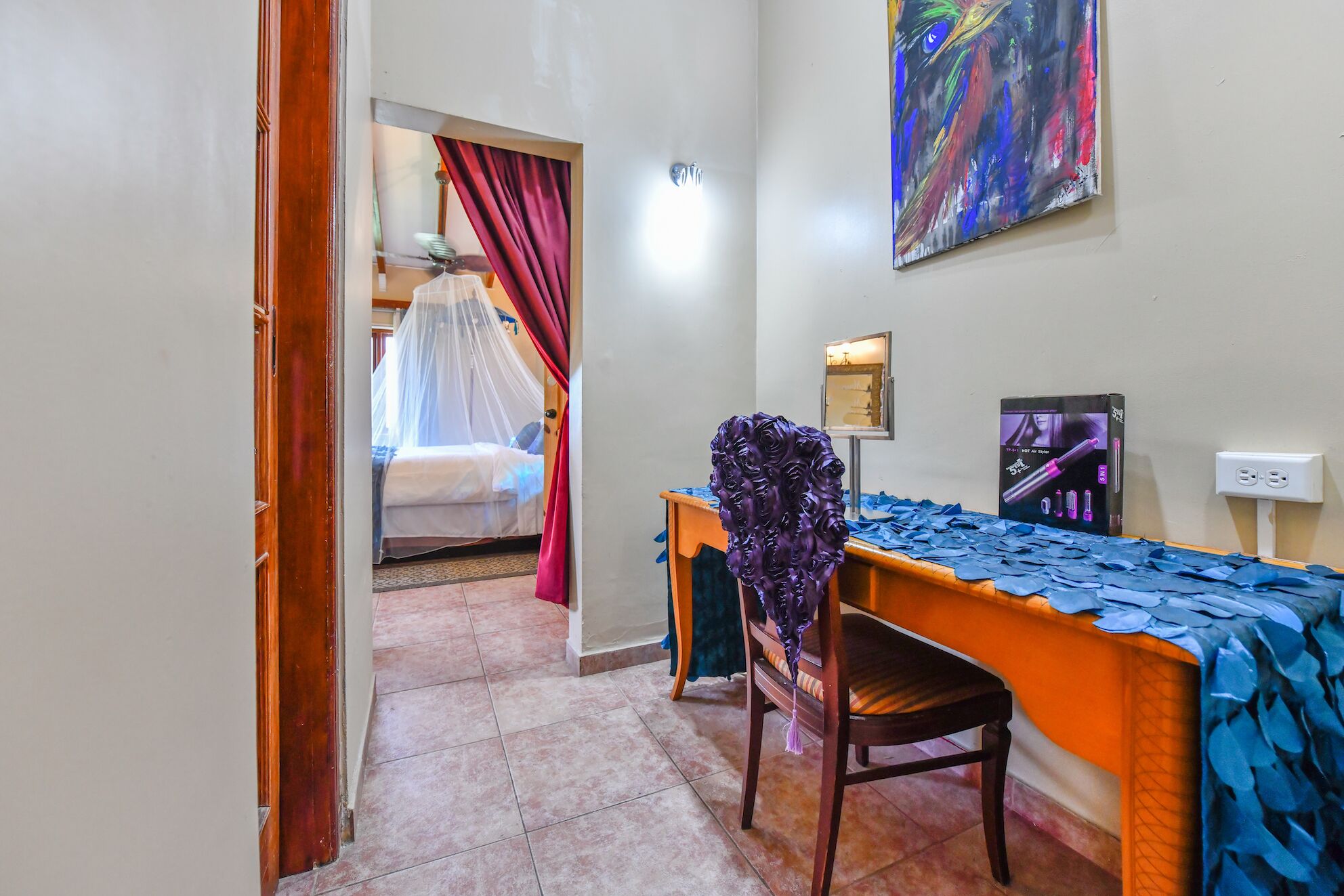 A hotel room with a bed, a desk, a chair, and a painting on the wall.