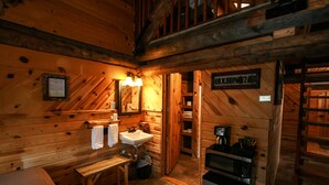 A wooden cabin interior with a wooden bench, a sink, a microwave, and a ladder. - Judith Mountain Lodge (Lewistown)