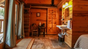 A wooden cabin bathroom with a sink, mirror, and a chair. - Judith Mountain Lodge (Lewistown)