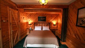 Une chambre à coucher aux murs lambrissés, avec un grand lit, deux tables de chevet et un lustre.