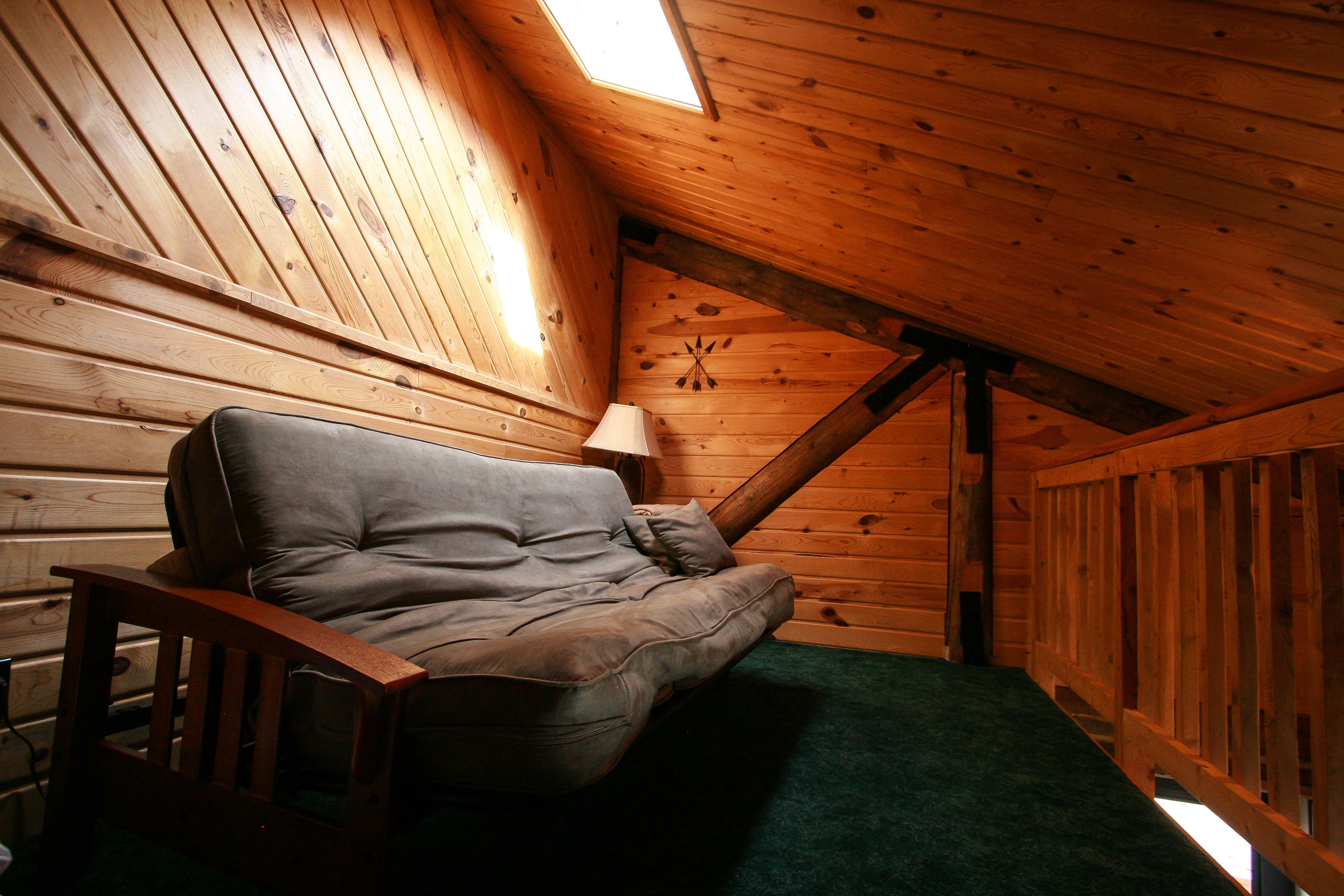 En hyggelig træhytte med sofa og lampe.