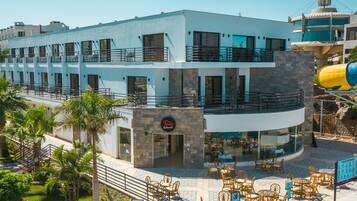 A hotel with a modern design, featuring a pool area with lounge chairs and a water slide.