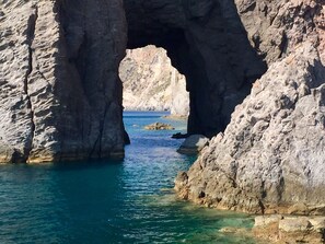 A natural rock formation with a large archway over a body of water.