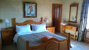 A bedroom with a wooden bed, two bedside tables with lamps, a dresser, a mirror, and a painting on the wall. - Ta Cikku, a luxury 5 bedroom with villa  with pool for family, friends and fun.  (Gharb)