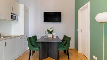 A modern kitchen with white cabinets, a microwave, and a dining area with a dark table and green chairs.
