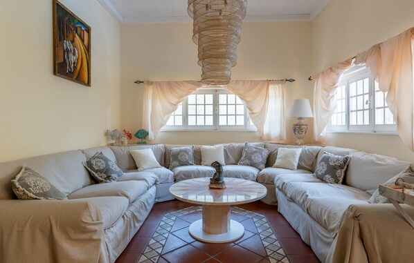 Ein Wohnzimmer mit einem beigefarbenen Ecksofa, einem runden Couchtisch und einem Bild an der Wand.