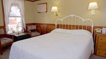 A neatly arranged bedroom with a single bed, a bedside table, a chair, and two wall-mounted lamps.