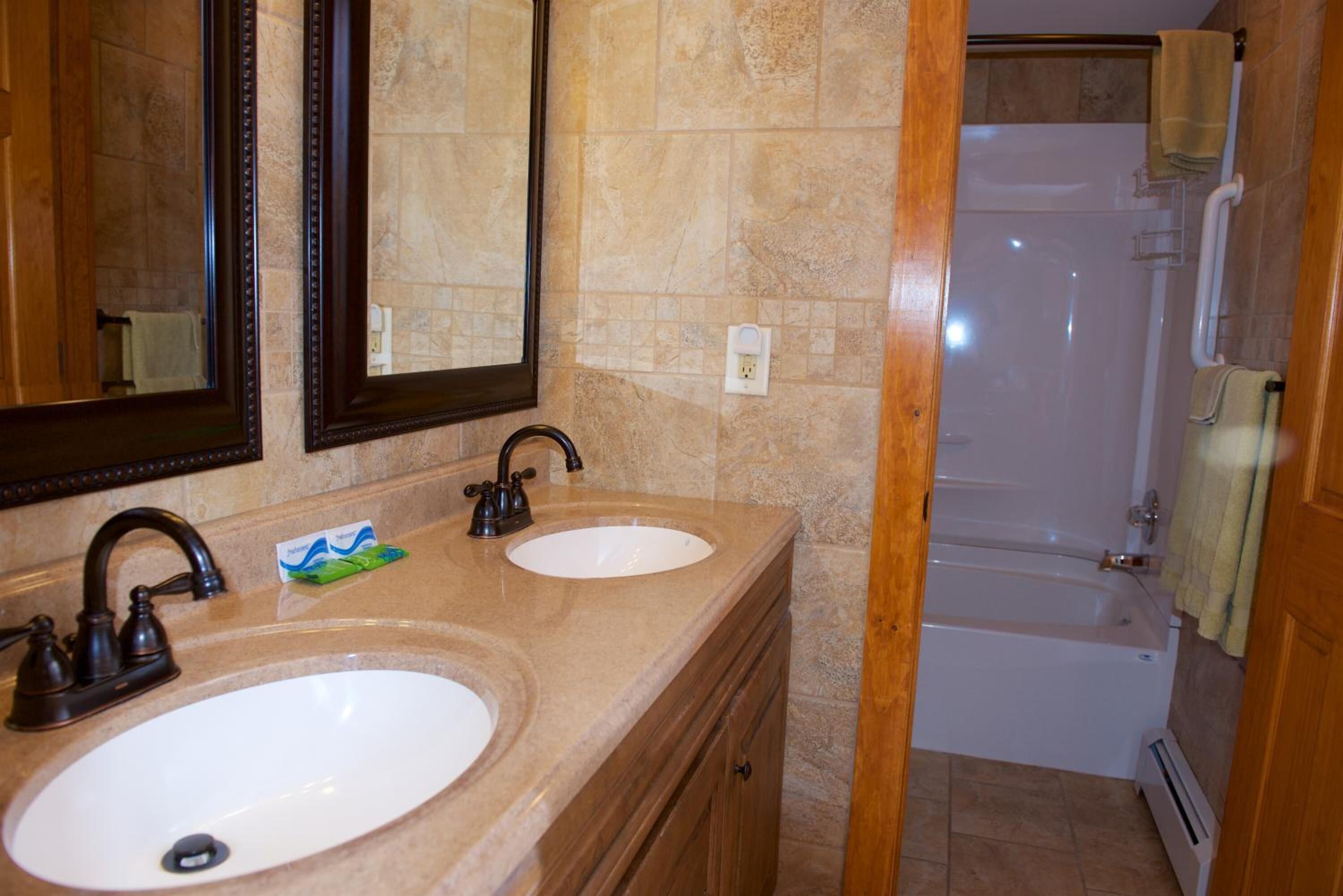 A bathroom with two sinks, a mirror, and a bathtub.