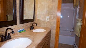 A bathroom with two sinks, a mirror, and a bathtub.