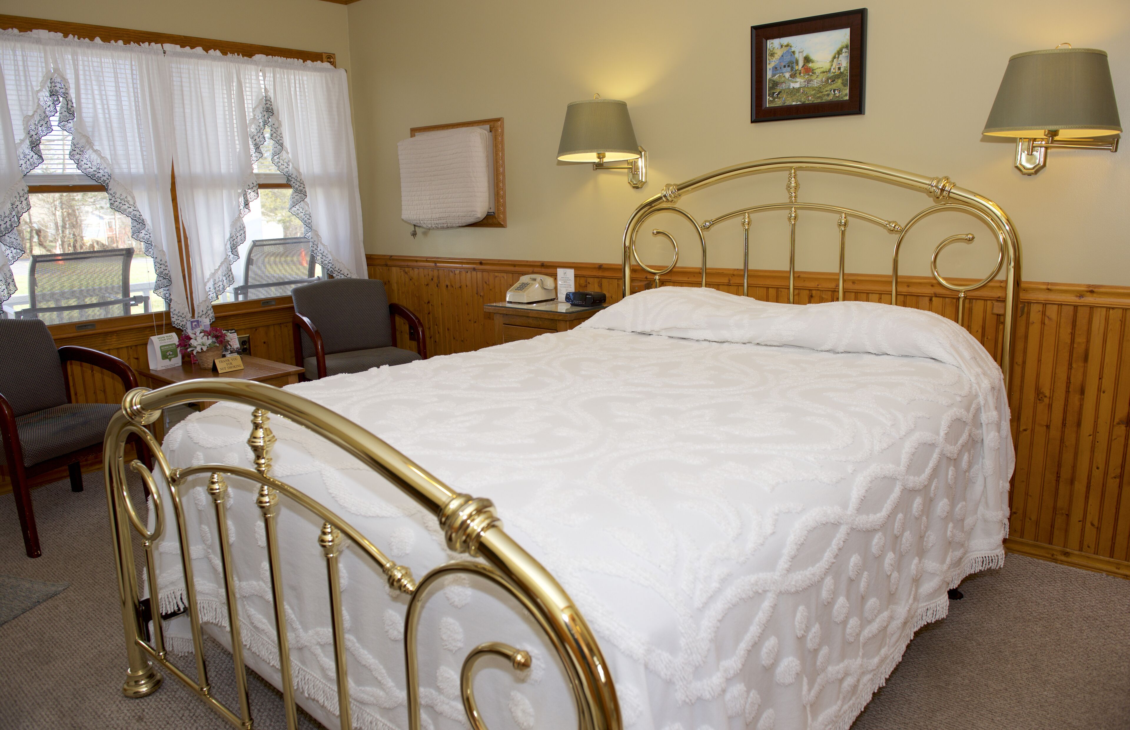 A hotel room with a bed, a desk, a chair, and two lamps.