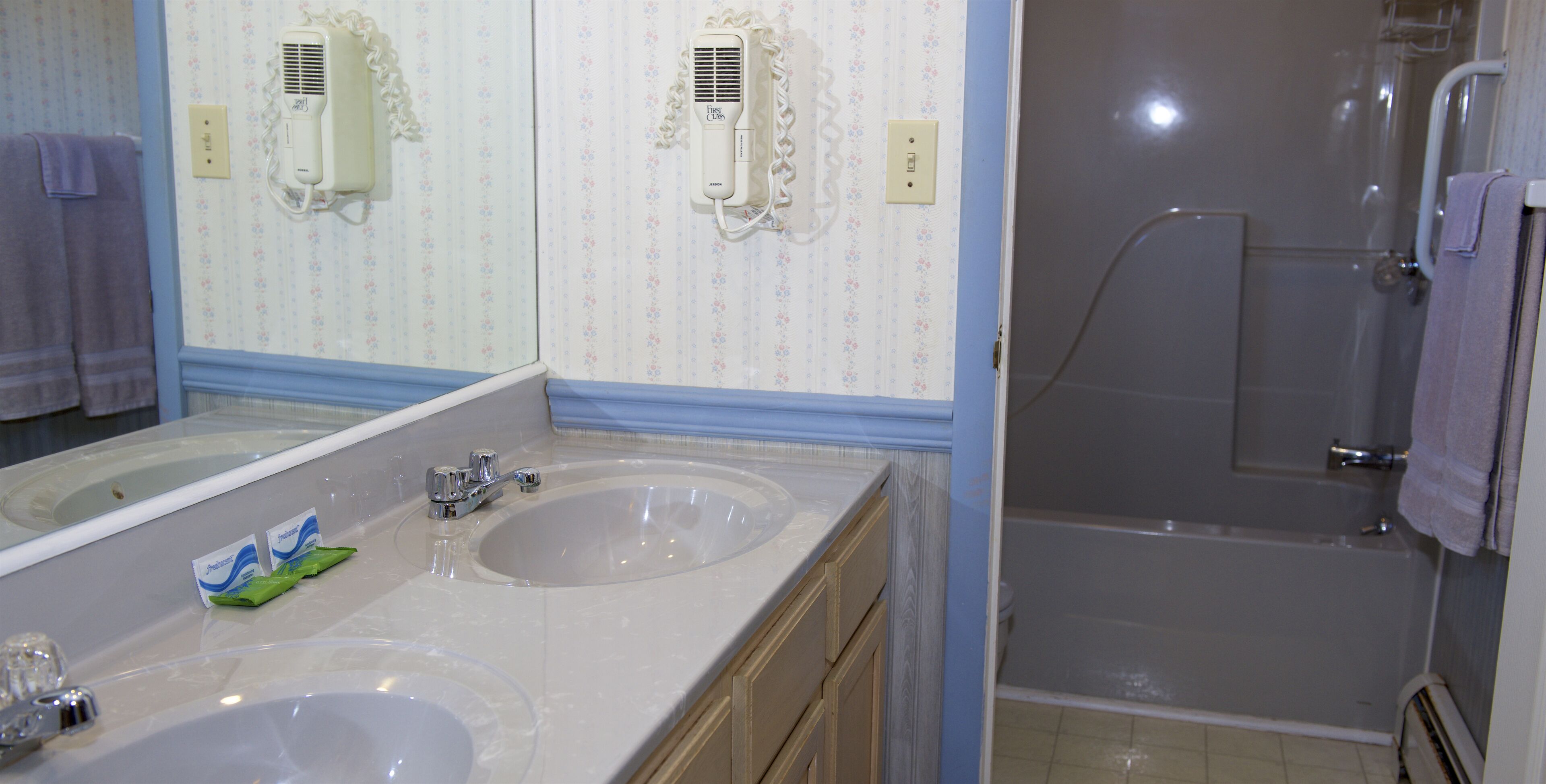 A bathroom with two sinks, a mirror, and a shower.